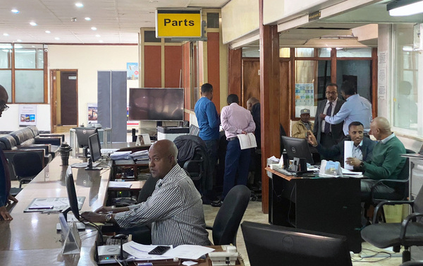 parts office with desks and laptops, men discussing