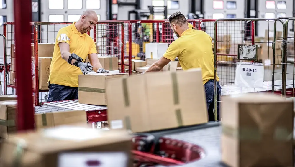Warehouse workers sorting packages on a conveyor belt