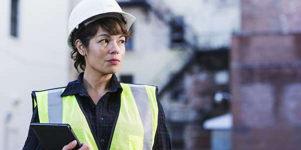 woman wearing a hard hat holding a digital tablet