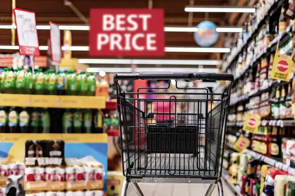 A shopping cart in a supermarket with a sign saying “Best Price” in the background