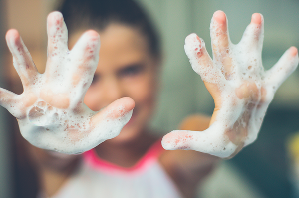child holds out soapy hands