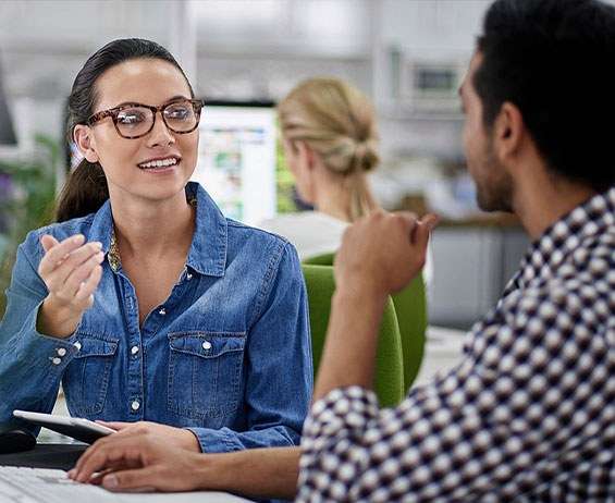 Two colleagues in an office setting collaborating and discussing business strategy with tablet device