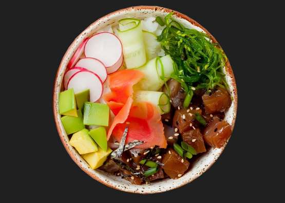 photo looking down at a poke bowl filled with fish and vegetables
