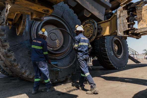 workers fixing the tire on a large tractor