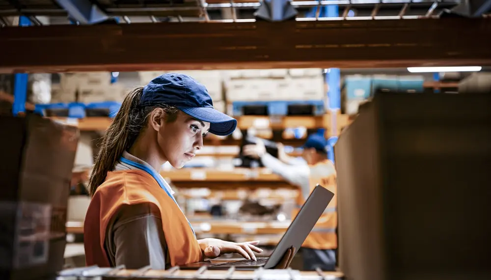 Female worker using laptop while working at distribution warehouse