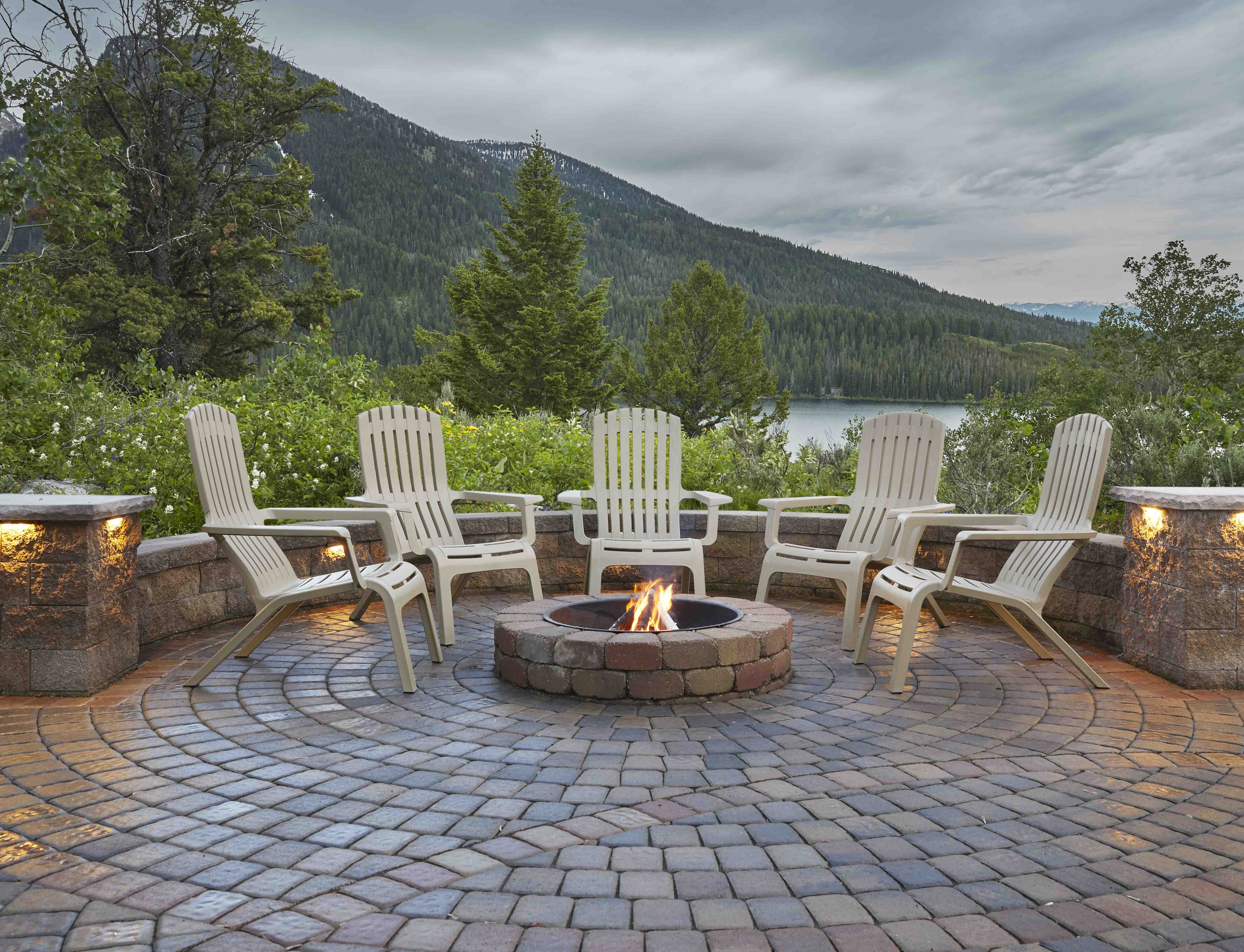 outdoor chairs around patio firepit with lake and mountains