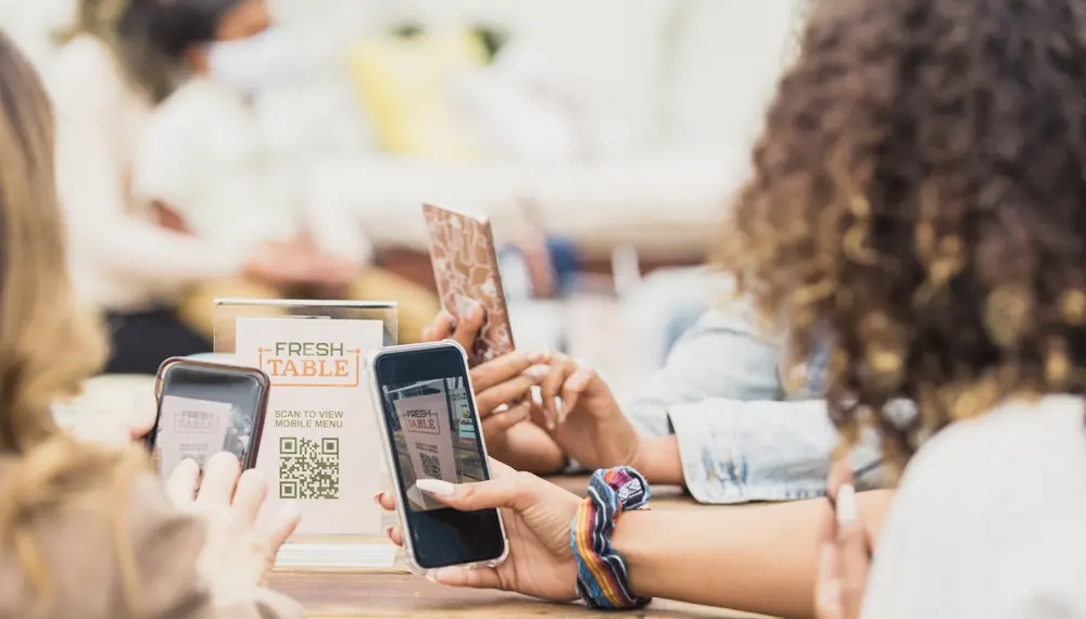 A group of friends sitting down at a restaurant scanning a QR code for the menu