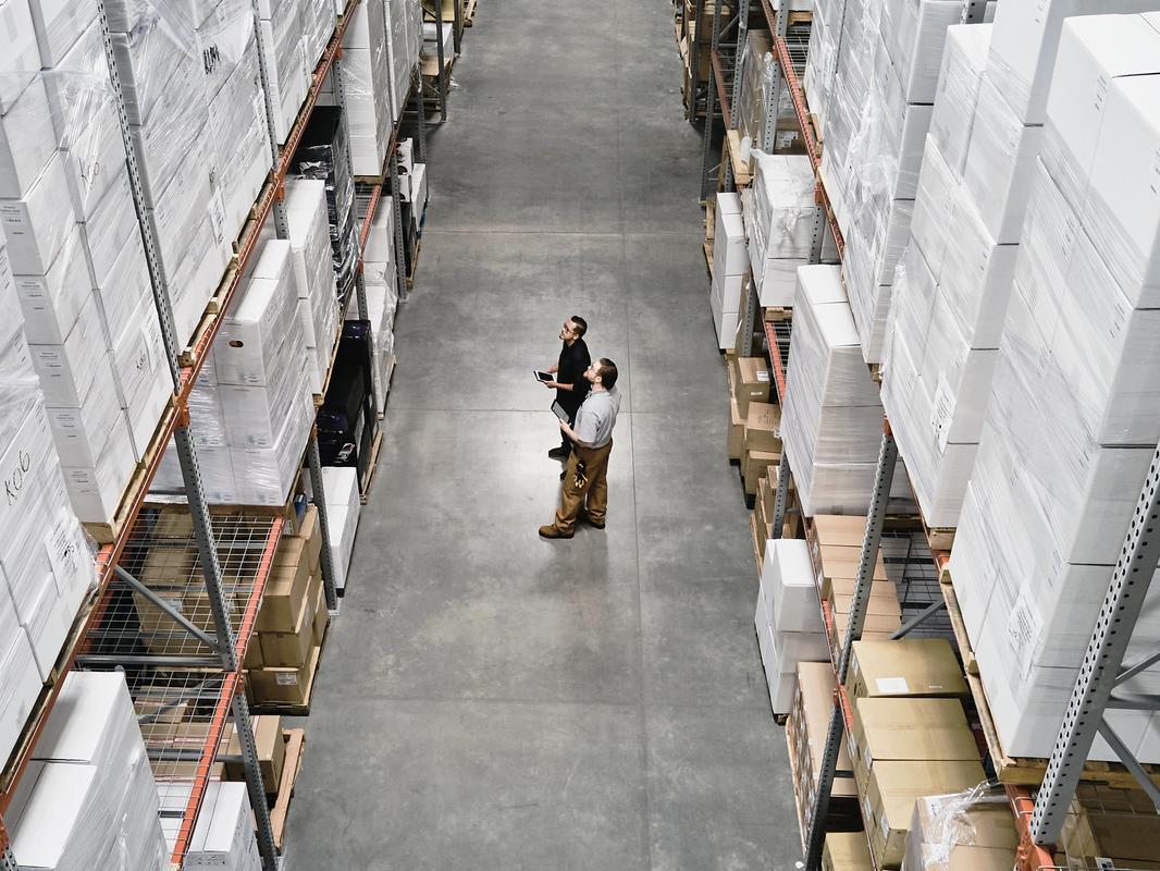 Warehouse employees in discussion while checking inventory with digital tablets