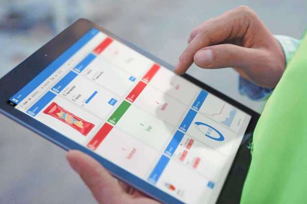 Factory worker controls operations with Infor MES software on a tablet