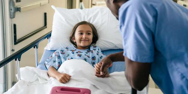 African American male nurse child patient hospital bed hallway