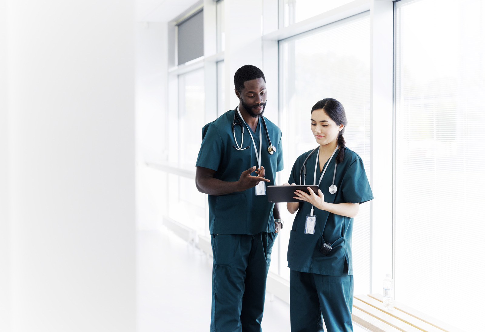 Two-doctors-hospital-hallway-discussing-electronic-patient-record_HealthCare_Getty