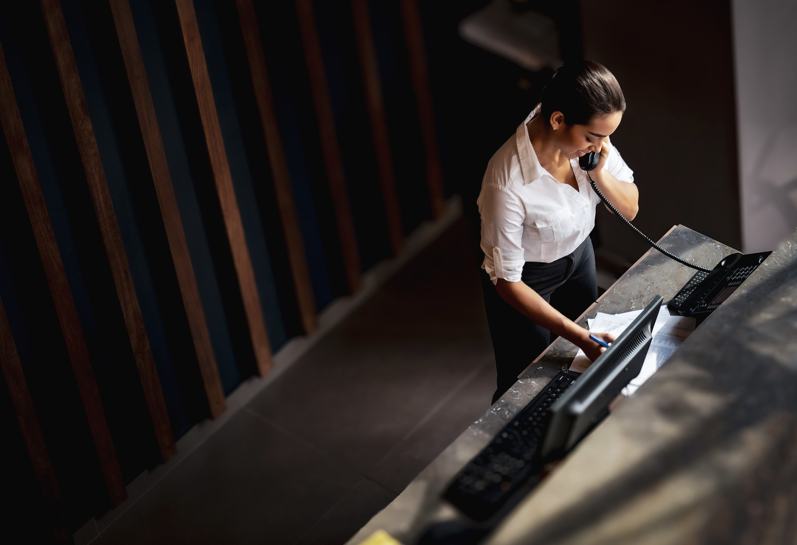 Latin American hotel receptionist taking a phone call
