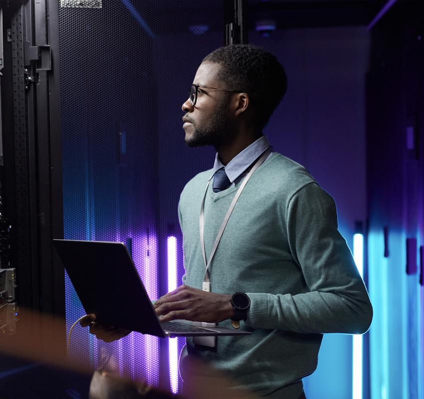 African American data engineer holding
  laptop server room