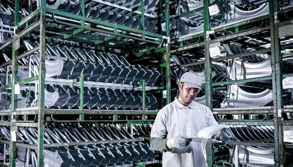 Car plant worker with car parts