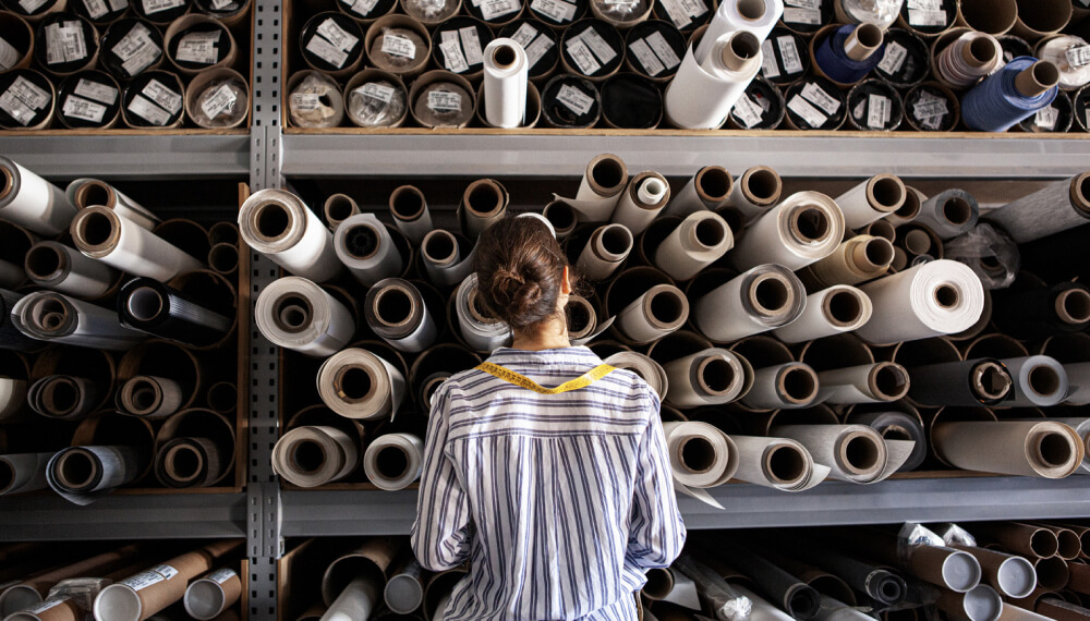 Woman choosing fabric from a stack of rolls