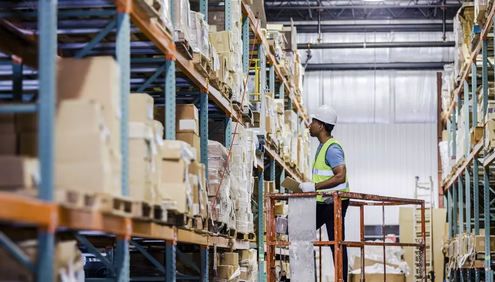 Warehouse worker checks inventory on high shelves