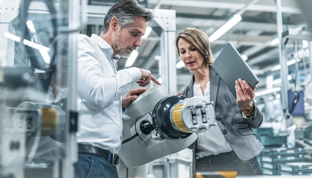 1175118071 Businesswoman and
  man talking at assembly robot in a factory Getty Edited tif
