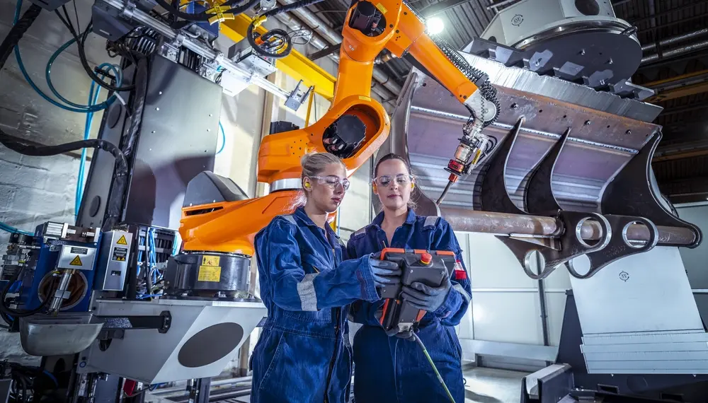Engineers programming a robot in a factory 