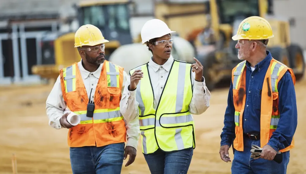 Woman directing construction workers, walking thru site