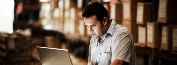 Buyer using an advanced workspace on a laptop in a warehouse 
