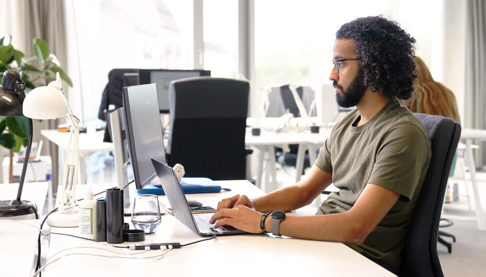 Male CAD designer sitting at his work desk using Infor PLM on his computer to streamline his product development process